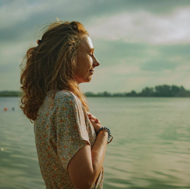 Vrouw in rust bij het water, met de hand op haar hart